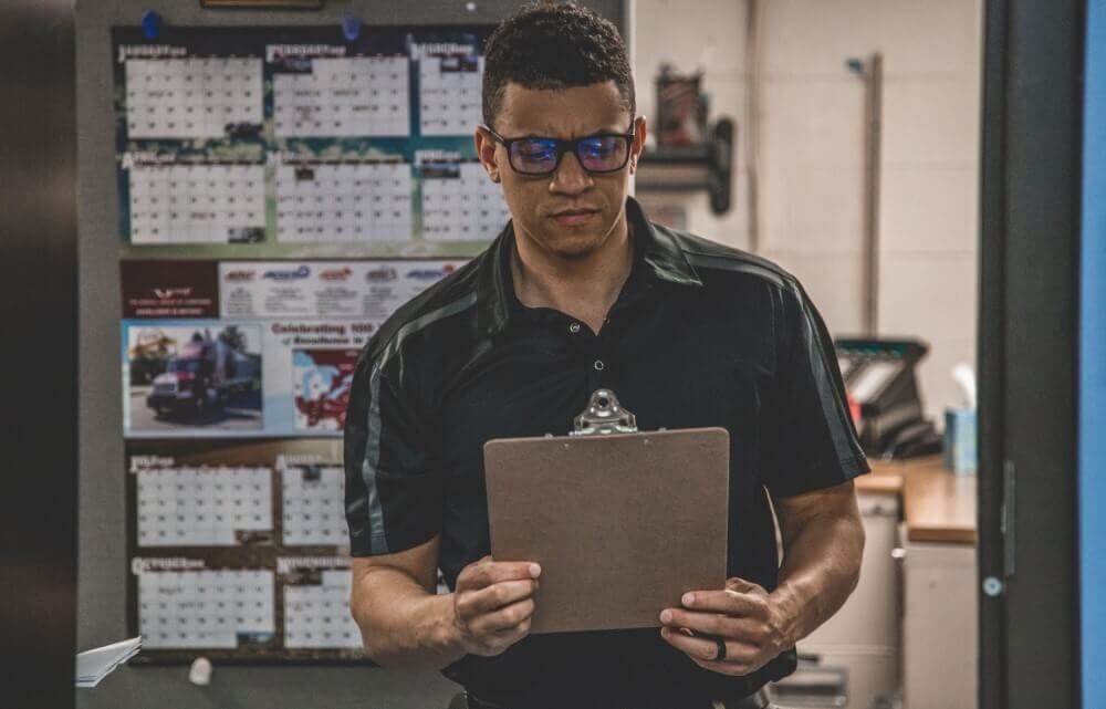 Man holding clipboard inside warehouse for inspection